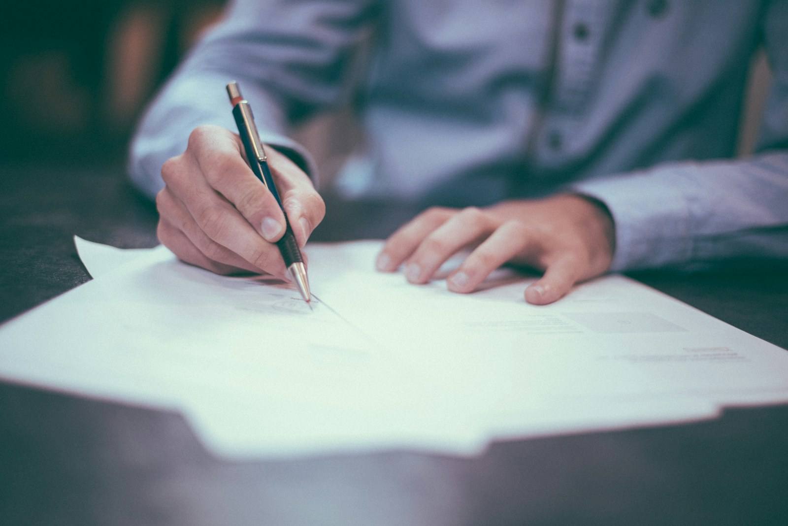 A researcher writing notes by hand at a desk